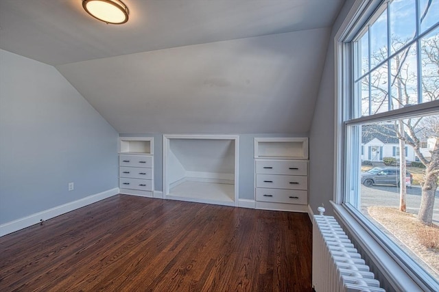 bonus room featuring dark wood-style floors, built in shelves, baseboards, and vaulted ceiling