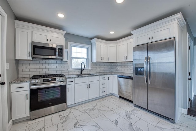 kitchen featuring appliances with stainless steel finishes, light stone countertops, marble finish floor, white cabinetry, and a sink