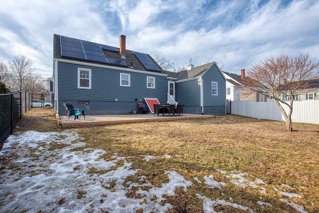 rear view of house featuring a lawn, solar panels, a fenced backyard, a chimney, and a patio area