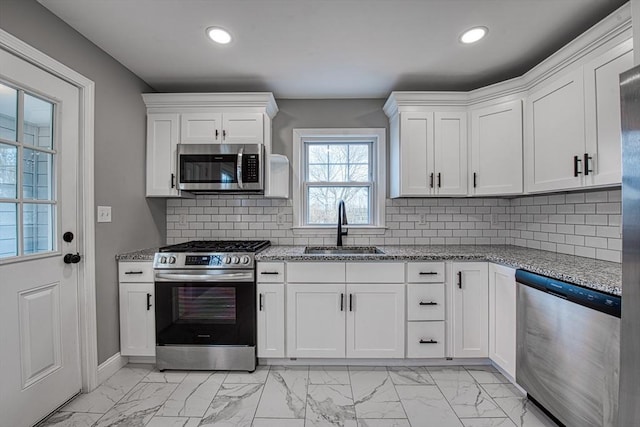 kitchen with appliances with stainless steel finishes, marble finish floor, white cabinets, and a sink