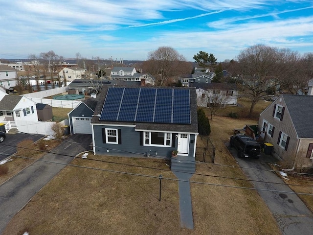 view of front of home with solar panels, a front yard, a garage, a residential view, and driveway