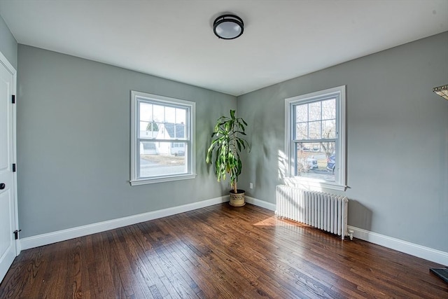 spare room featuring baseboards, dark wood finished floors, and radiator