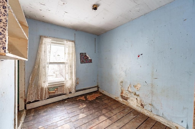 empty room with a baseboard heating unit and hardwood / wood-style flooring