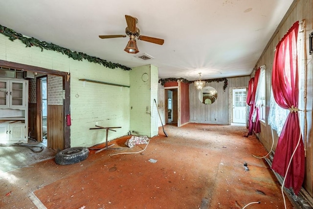 miscellaneous room featuring brick wall and ceiling fan with notable chandelier