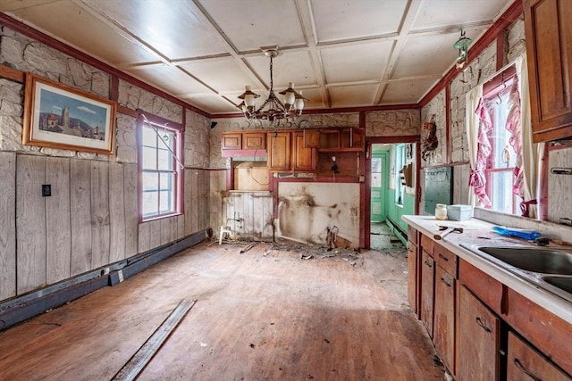 kitchen with decorative light fixtures, an inviting chandelier, sink, light hardwood / wood-style flooring, and coffered ceiling