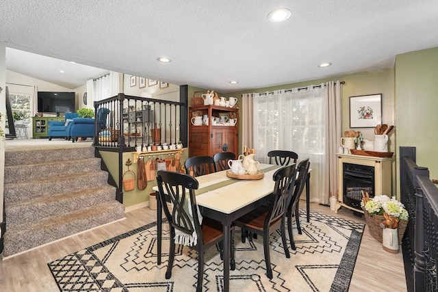 dining room with lofted ceiling, plenty of natural light, a textured ceiling, and light hardwood / wood-style flooring