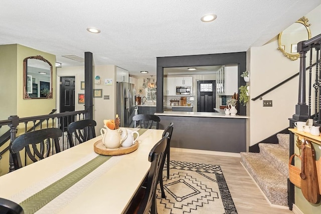 dining space featuring a textured ceiling and light wood-type flooring