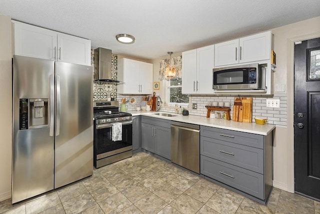 kitchen featuring appliances with stainless steel finishes, gray cabinetry, wall chimney range hood, and white cabinets