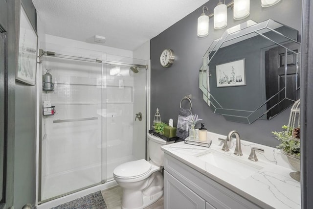 bathroom with vanity, a textured ceiling, a shower with door, and toilet