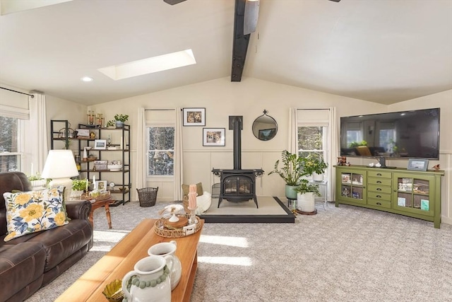 living room featuring a wood stove, lofted ceiling with skylight, and carpet