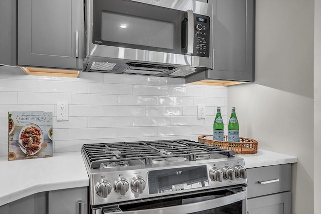 kitchen featuring gray cabinets, light countertops, appliances with stainless steel finishes, and decorative backsplash