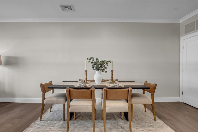 dining room featuring wood finished floors, ornamental molding, and visible vents