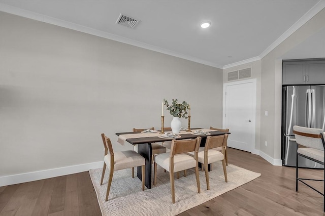 dining space featuring ornamental molding, visible vents, baseboards, and wood finished floors