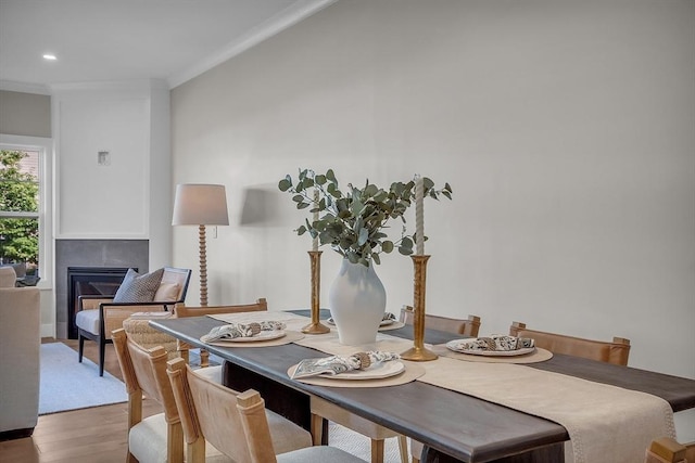 dining area featuring crown molding, wood finished floors, a glass covered fireplace, and recessed lighting