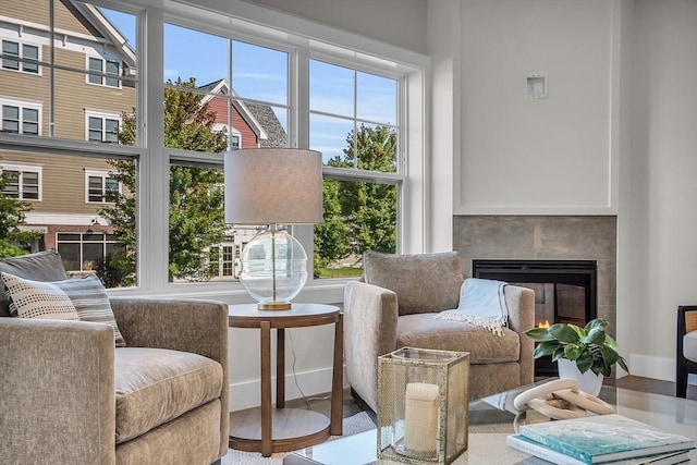 living area with plenty of natural light, a lit fireplace, and wood finished floors