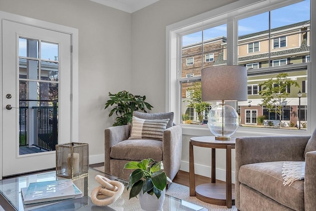 sitting room with baseboards, wood finished floors, and a healthy amount of sunlight