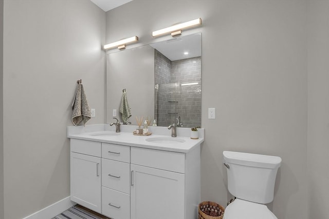 bathroom with toilet, double vanity, a sink, and a stall shower