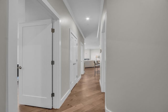 corridor with light wood-style flooring, baseboards, ornamental molding, and recessed lighting