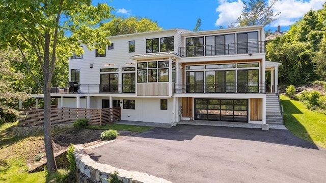 135 Beach St, Cohasset, MA 02025 - rear view of house with a balcony, asphalt driveway, a sunroom, and a garage