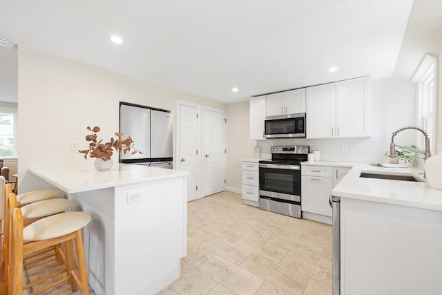 11-13 Turner Ter, Newton, MA 02460 - kitchen featuring appliances with stainless steel finishes, a peninsula, a kitchen breakfast bar, white cabinetry, and light countertops