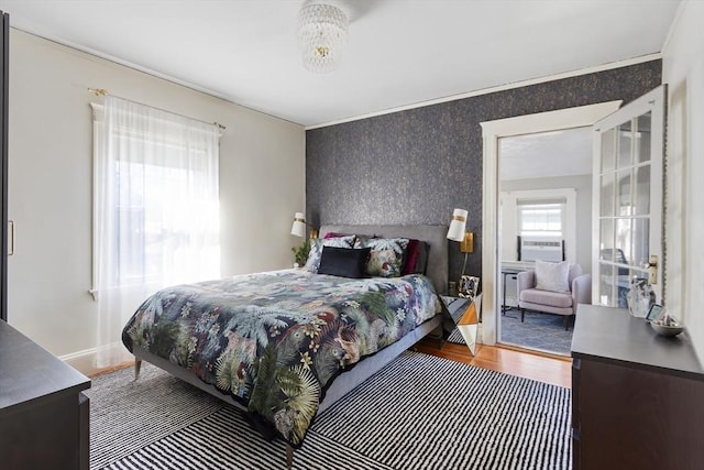 bedroom featuring wallpapered walls, wood finished floors, and baseboards