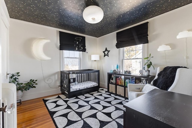 bedroom featuring baseboards, crown molding, and wood finished floors