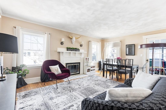 living room featuring a fireplace with flush hearth, a wealth of natural light, crown molding, and wood finished floors