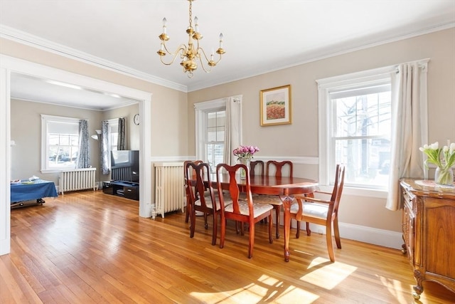 dining space with radiator, crown molding, light wood finished floors, and an inviting chandelier