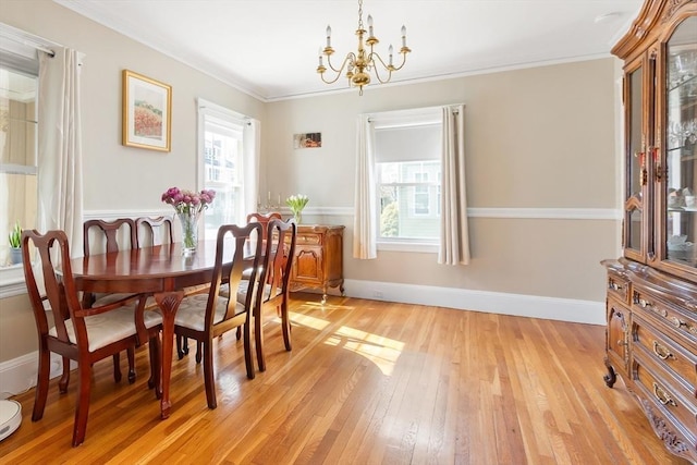 dining area with baseboards, crown molding, light wood-style flooring, and an inviting chandelier