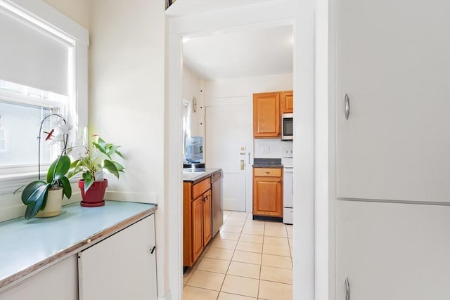 kitchen with light tile patterned floors, stainless steel appliances, light countertops, and brown cabinetry