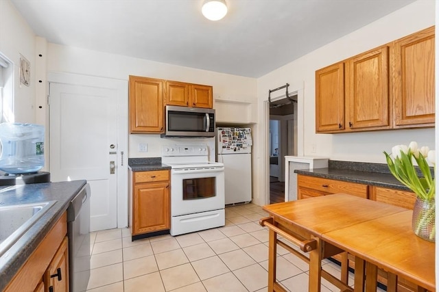 kitchen with stainless steel appliances, dark countertops, brown cabinetry, and light tile patterned floors