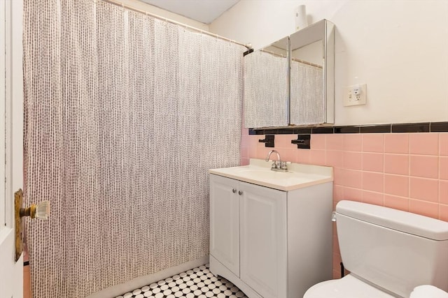 full bath with toilet, tile walls, and vanity