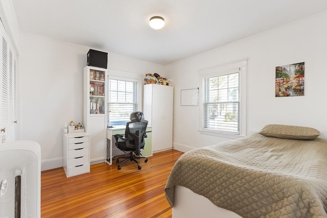 bedroom with light wood-type flooring, multiple windows, and baseboards