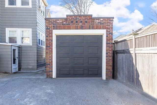 garage featuring driveway and fence