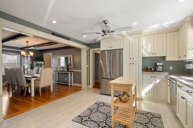 kitchen with beamed ceiling, cream cabinetry, appliances with stainless steel finishes, light wood finished floors, and light countertops