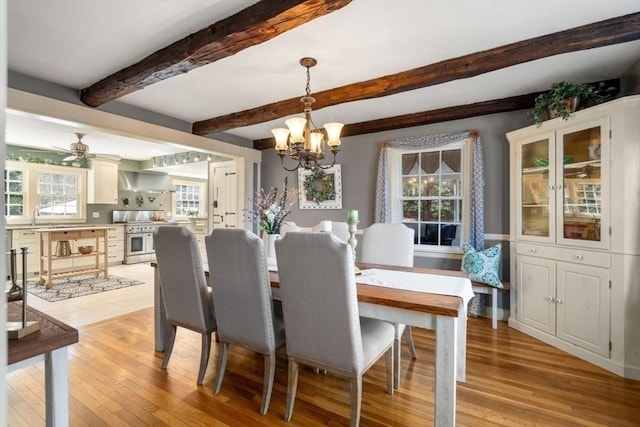 dining space with beam ceiling, a notable chandelier, and light wood-type flooring