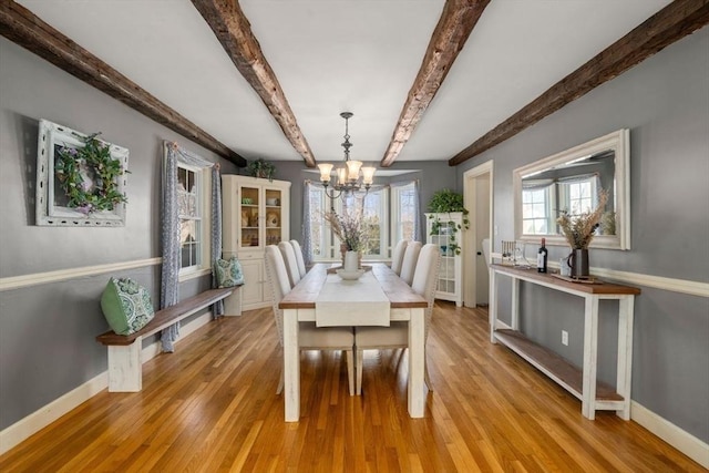 dining area featuring baseboards, light wood-type flooring, and an inviting chandelier