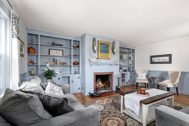 living room with baseboards, built in shelves, wood finished floors, and a fireplace