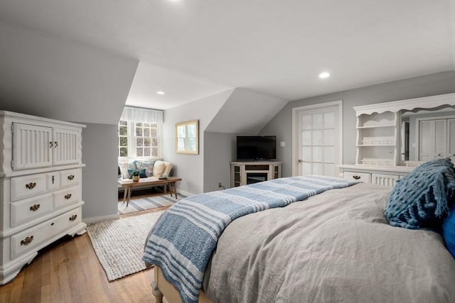 bedroom with recessed lighting, baseboards, lofted ceiling, and wood finished floors