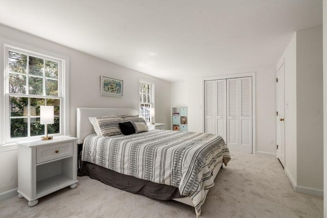 bedroom featuring light colored carpet, a closet, and baseboards