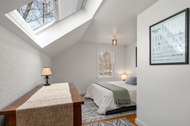 bedroom with lofted ceiling with skylight, wood finished floors, and baseboards