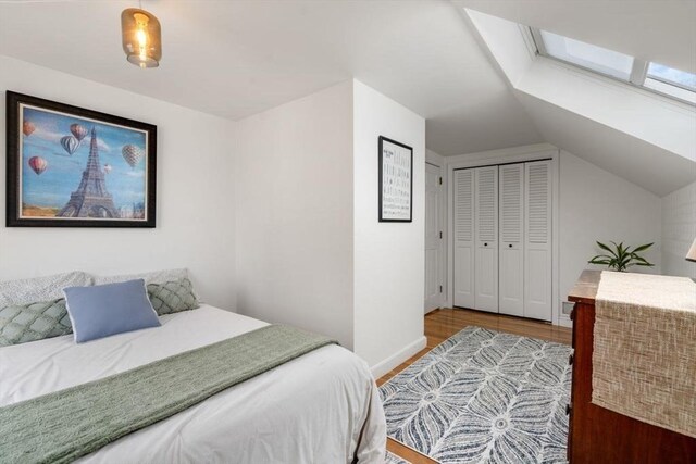 bedroom with baseboards, lofted ceiling, a closet, and wood finished floors