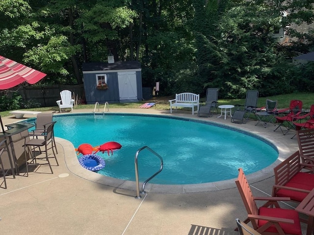 view of swimming pool with a patio, a fenced in pool, fence, a shed, and a diving board