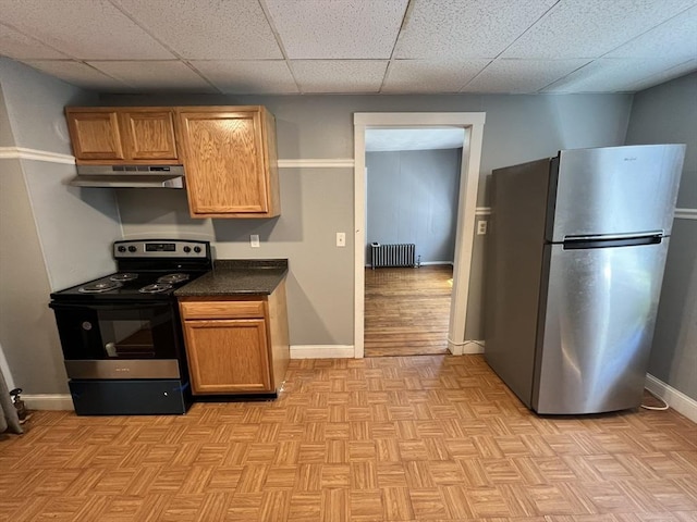 kitchen with radiator, a drop ceiling, light parquet floors, and stainless steel appliances