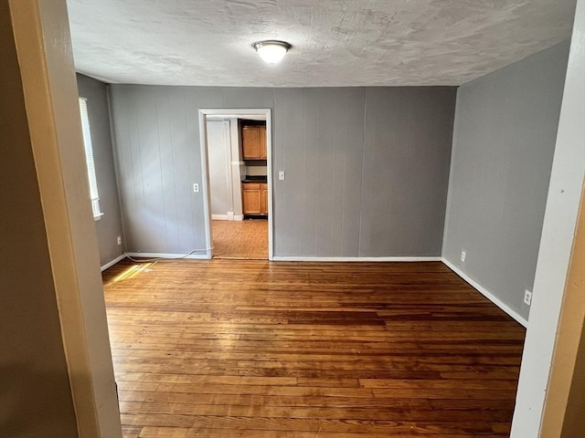 unfurnished room featuring wood-type flooring and a textured ceiling