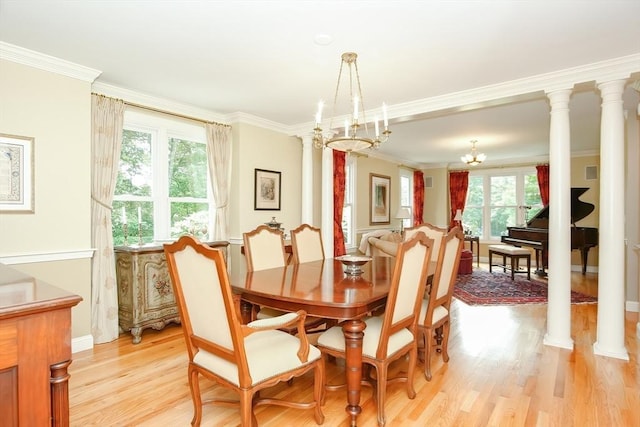 dining room featuring an inviting chandelier, crown molding, ornate columns, and light wood-type flooring