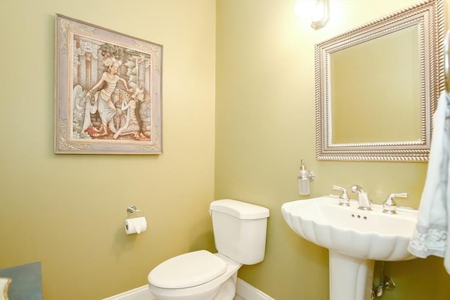half bathroom featuring baseboards and toilet