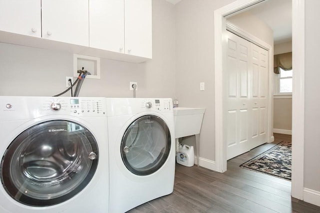 laundry area with washing machine and clothes dryer, cabinet space, wood finished floors, and baseboards