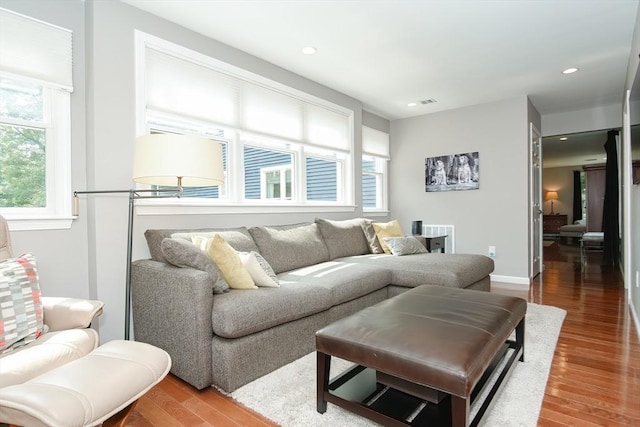 living area featuring baseboards, wood finished floors, and recessed lighting