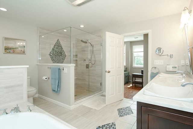 full bathroom with visible vents, a shower stall, double vanity, toilet, and a sink
